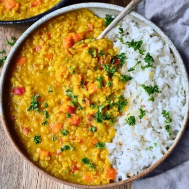 Creamy red lentil dahl served in a bowl with herbs and spices