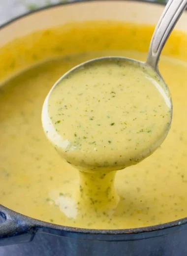 Bowl of creamy zucchini soup garnished with herbs and served with bread