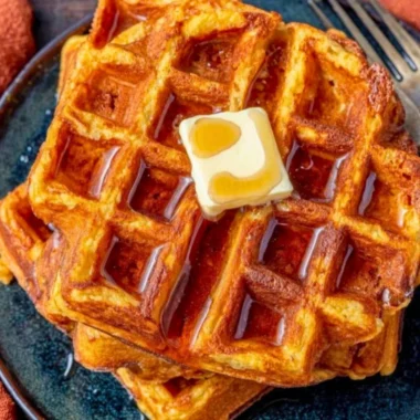 Delicious French toast waffles drizzled with syrup and topped with fresh berries