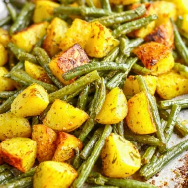 Delicious oven-roasted potatoes with green beans served on a plate.