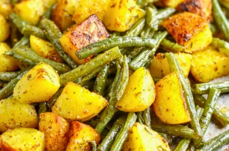 Delicious oven-roasted potatoes with green beans served on a plate.