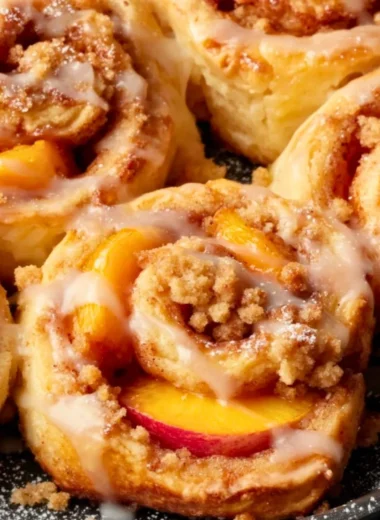 Fresh Peach Cobbler Cinnamon Rolls topped with glaze and cinnamon