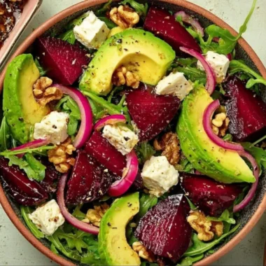 Roasted Beet Arugula Salad topped with Feta and Walnuts on a white plate