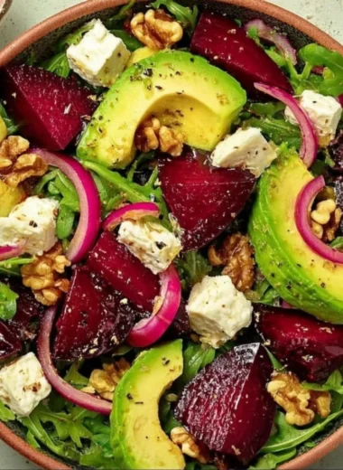 Roasted Beet Arugula Salad topped with Feta and Walnuts on a white plate