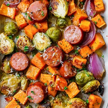 Sheet-pan sausage dish with colorful fall vegetables on a baking sheet.