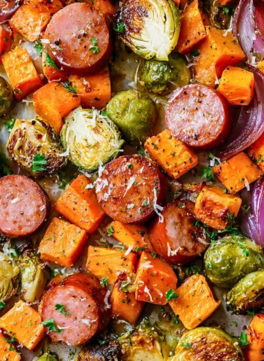 Sheet-pan sausage dish with colorful fall vegetables on a baking sheet.