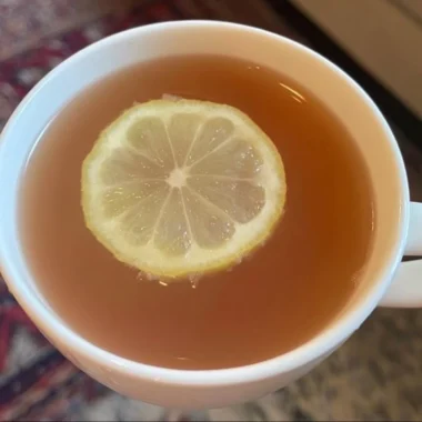 A refreshing glass of Citrus Mint Peach Tea with mint and peach slices.