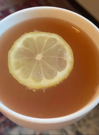 A refreshing glass of Citrus Mint Peach Tea with mint and peach slices.