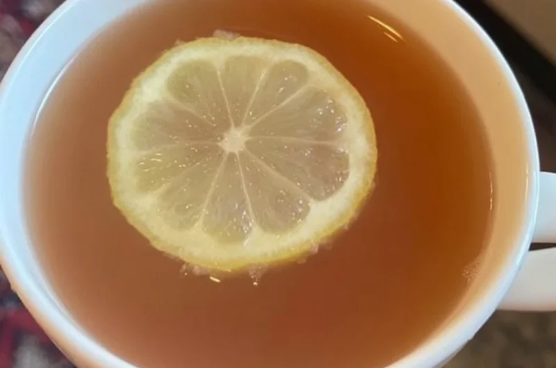 A refreshing glass of Citrus Mint Peach Tea with mint and peach slices.