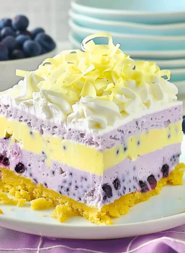 A vibrant slice of lemon blueberry lasagna topped with fresh blueberries and lemon zest.