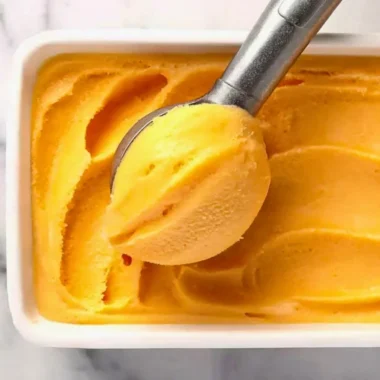 Delicious homemade Peach Sorbet served in a bowl with fresh peach slices