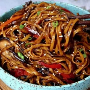 Colorful vegetable stir-fry noodles cooked in a wok with fresh ingredients.