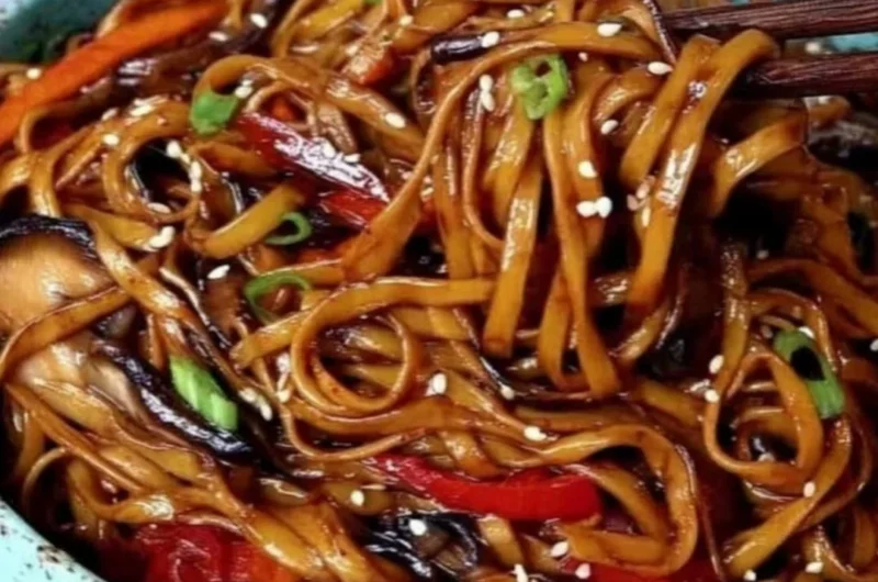 Colorful vegetable stir-fry noodles cooked in a wok with fresh ingredients.