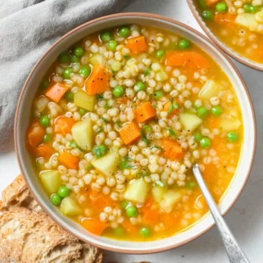 Bowl of delicious barley soup with vegetables and herbs