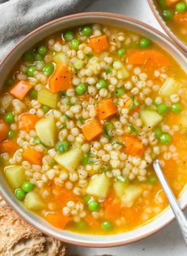 Bowl of delicious barley soup with vegetables and herbs