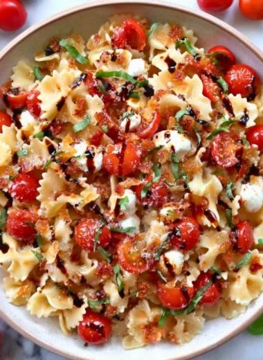 A colorful bowl of Bruschetta Pasta Salad with tomatoes, basil, and dressing