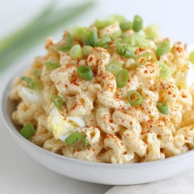 Bowl of creamy deviled egg pasta salad garnished with herbs and eggs