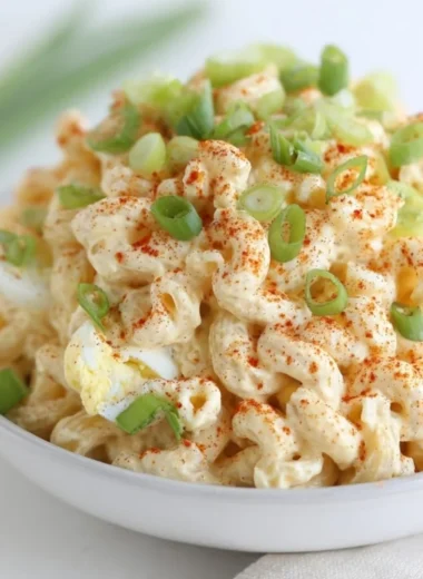 Bowl of creamy deviled egg pasta salad garnished with herbs and eggs