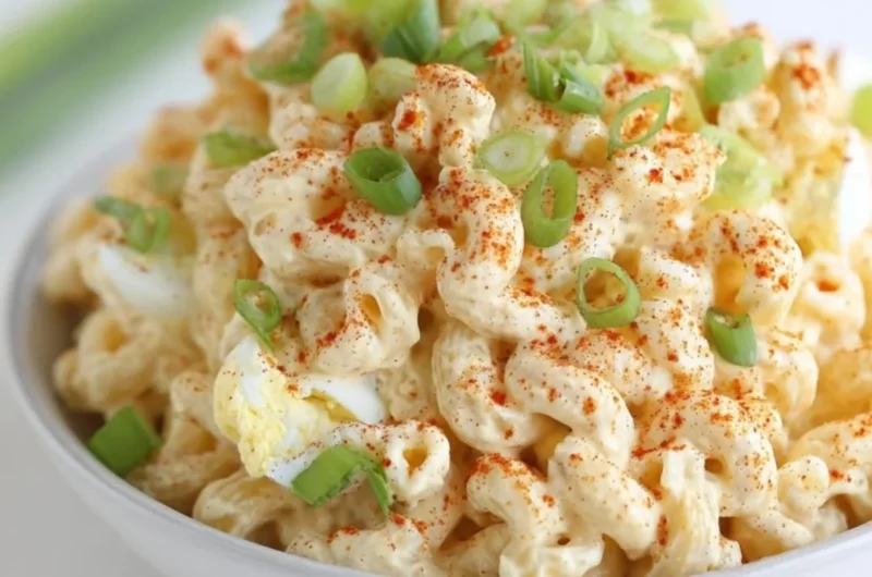 Bowl of creamy deviled egg pasta salad garnished with herbs and eggs