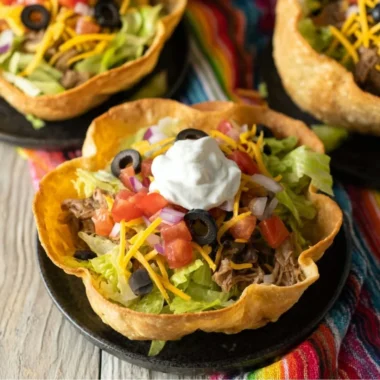 A colorful taco salad bowl filled with fresh toppings and ingredients