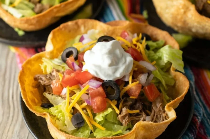 A colorful taco salad bowl filled with fresh toppings and ingredients