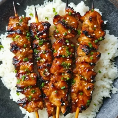 Grilled teriyaki chicken skewers garnished with sesame seeds.