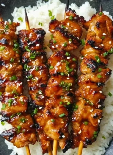 Grilled teriyaki chicken skewers garnished with sesame seeds.